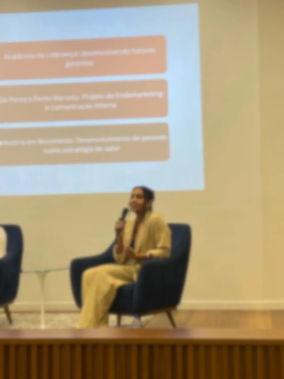 Palestrante sentada em um palco durante evento corporativo